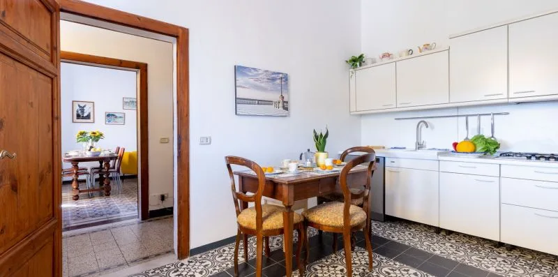 Una cocina luminosa con una mesa de madera junto a armarios blancos.