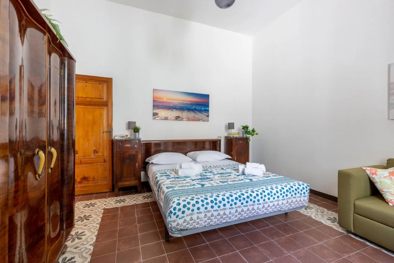 A bedroom with a double bed, wooden wardrobes, and a colorful patterned bedspread.