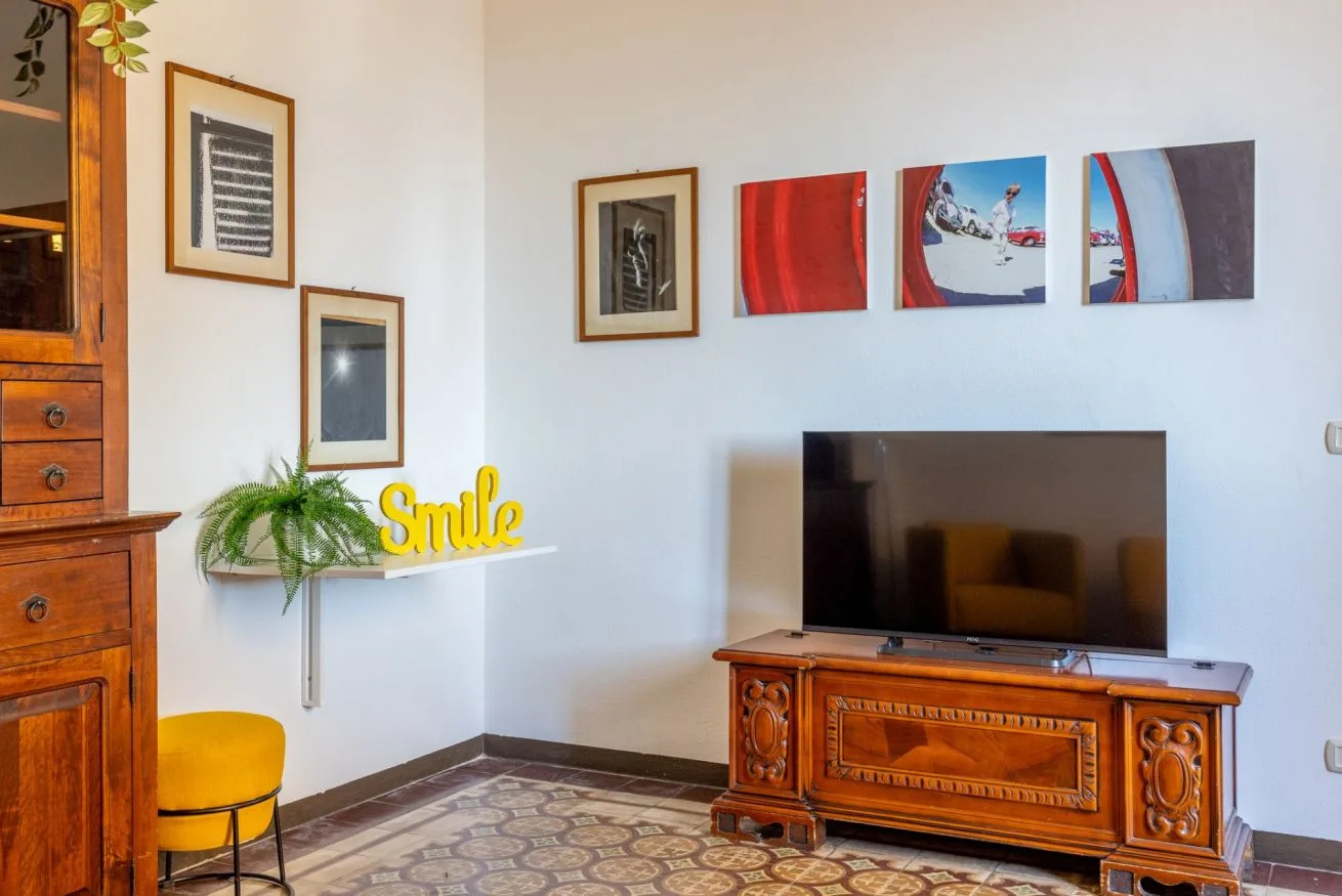 A living room with a television on a wooden cabinet and framed artwork.