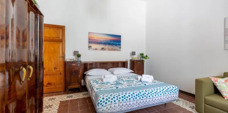 A bedroom with a double bed, wooden wardrobes, and a framed beach picture.
