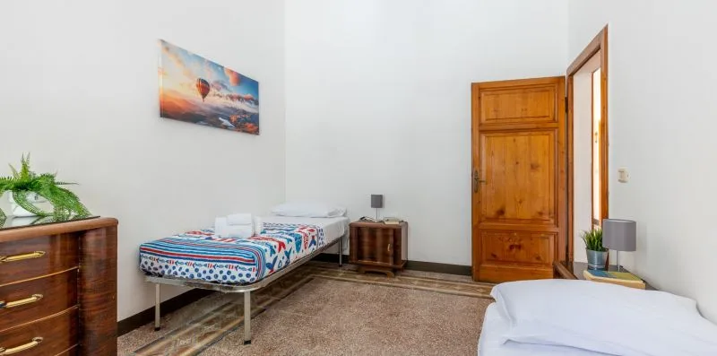 A bedroom with a single bed, bedside table, and wooden wardrobe.
