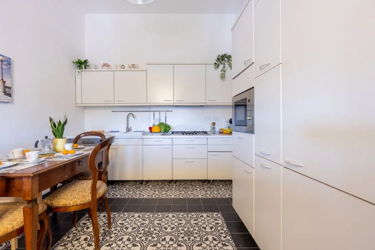 A bright kitchen with white cabinets, a countertop, and a dining table.