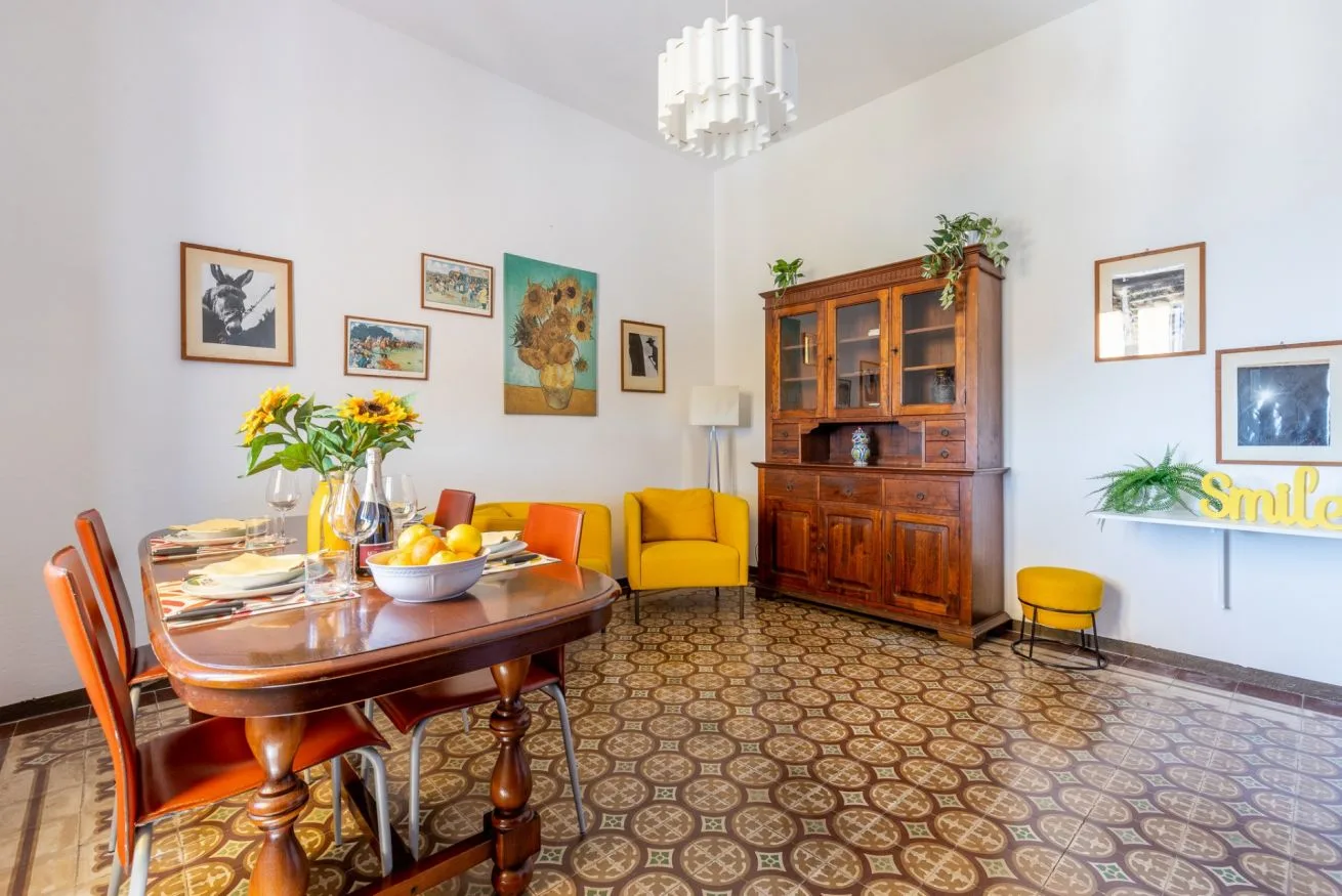 A dining room with a set table, yellow armchair, and wooden cabinet.