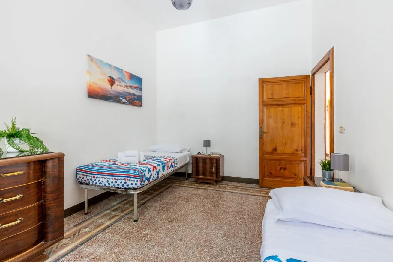 A bedroom with two beds, a wooden dresser, and a closed wooden door.