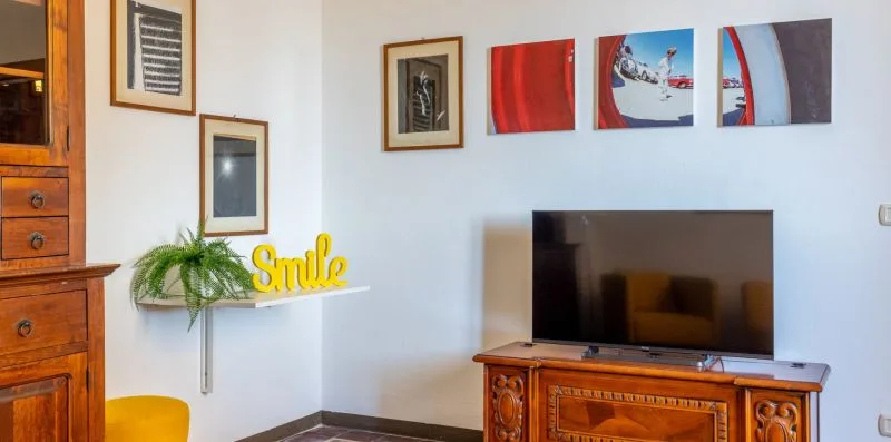 A living room with a television on a wooden cabinet and colorful wall art.