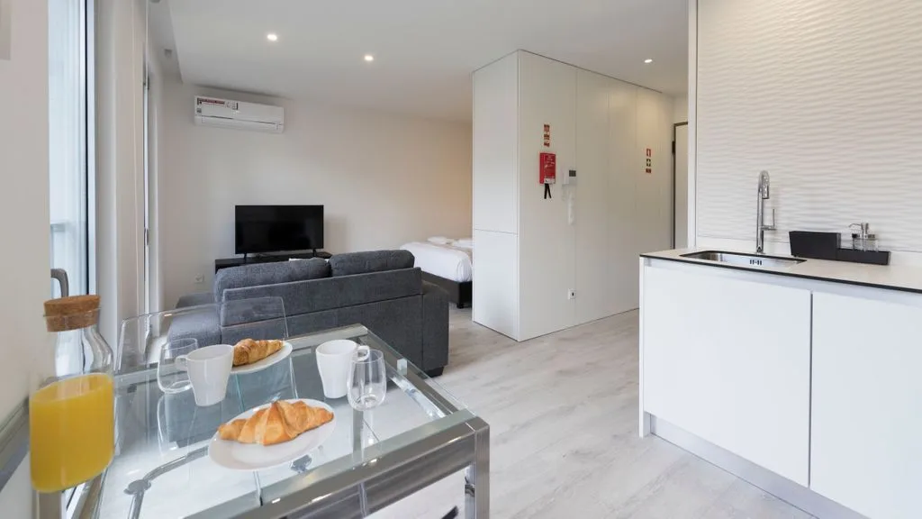 A bright loft living area with a glass dining table and kitchenette.