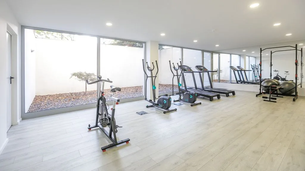 A bright gym with exercise bikes, treadmills, and large windows.