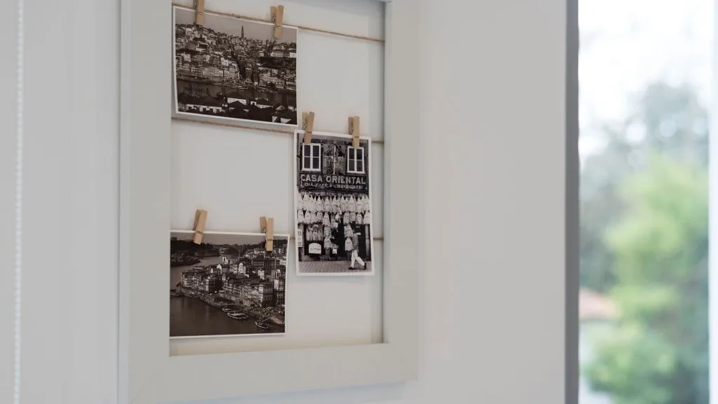 A framed display of black-and-white photographs hangs beside a window.
