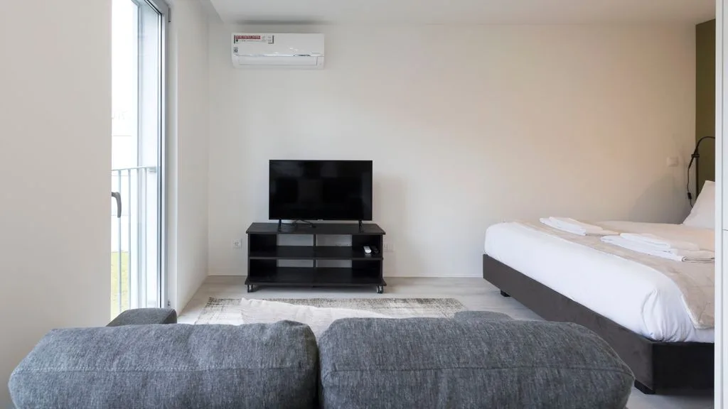 A bright bedroom with a bed, television, and seating.
