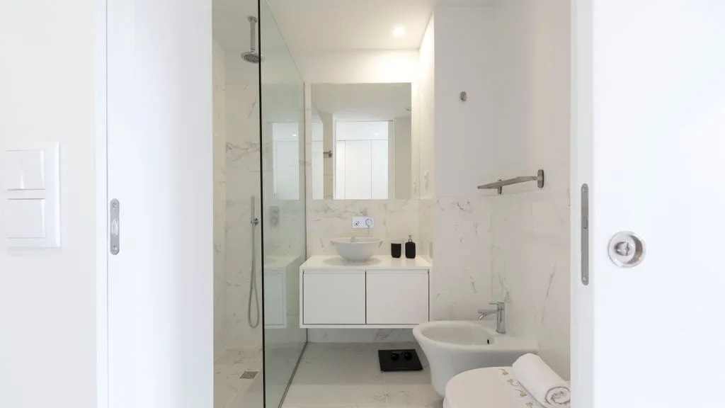A bright bathroom with a glass shower and a sink beneath a mirror.