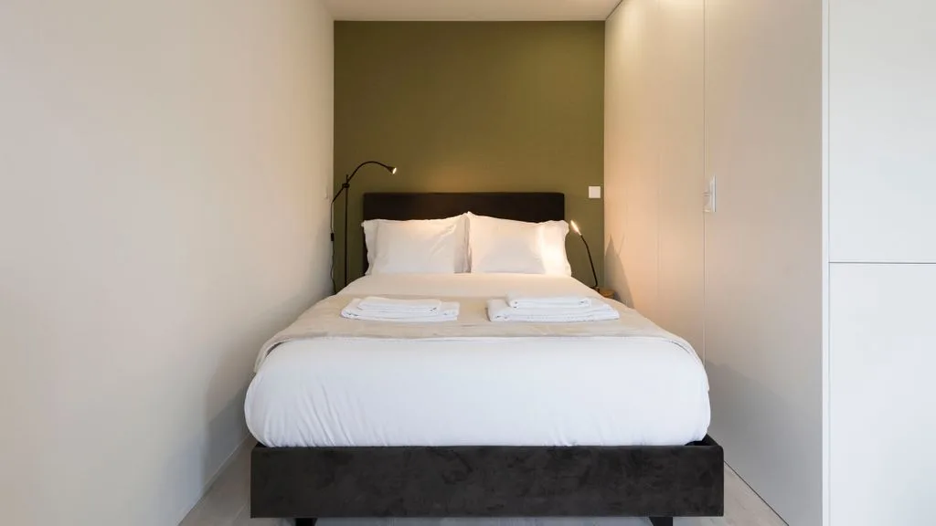 A bedroom with a neatly made bed and bedside lamps.