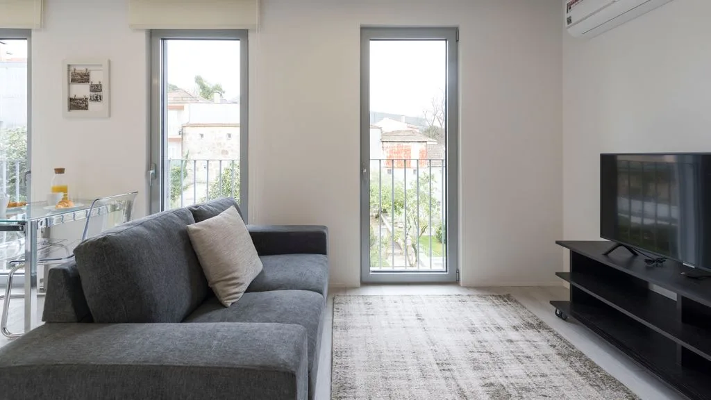 A bright living room with a gray seating area and television.