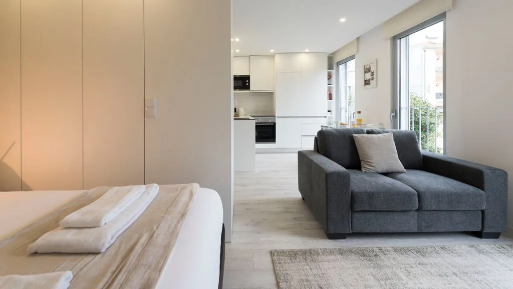 A bright living area with gray seating and an open kitchen.