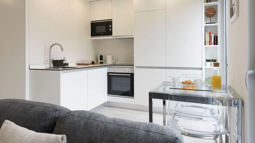 A bright kitchen and dining area with white cabinetry and a glass table.