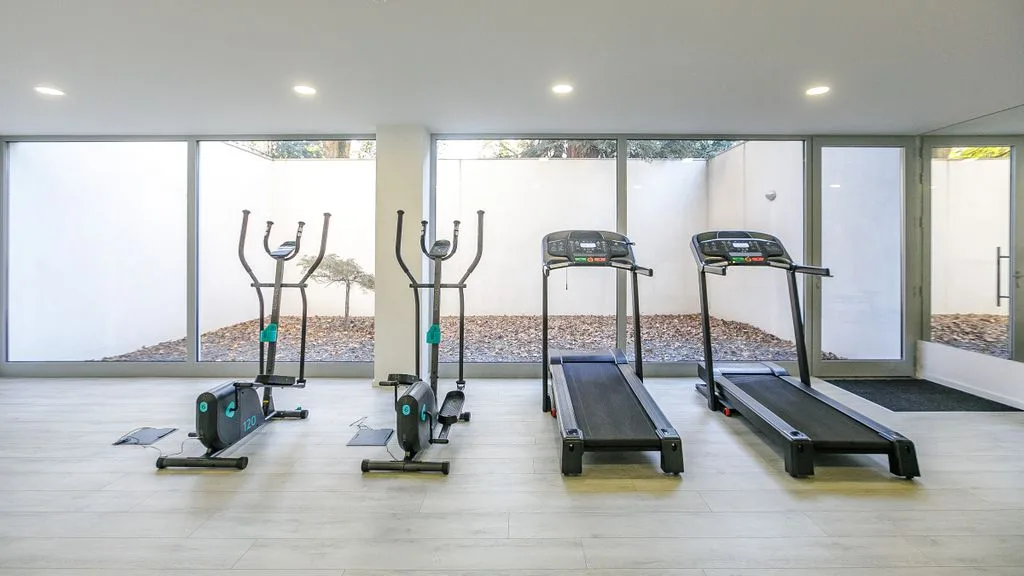 A bright gym with exercise machines and large windows.