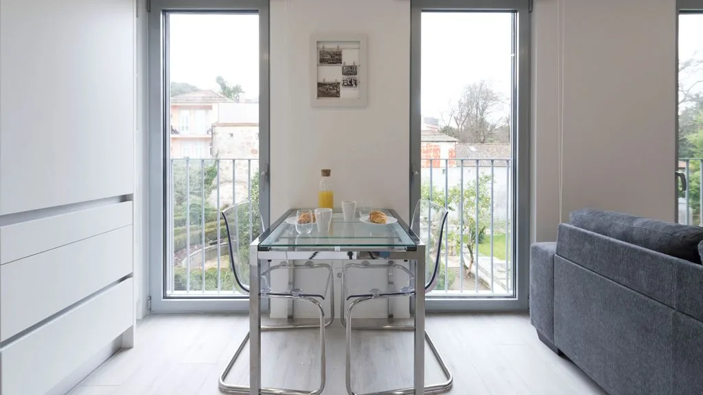 A bright dining area with a glass table beside tall windows.