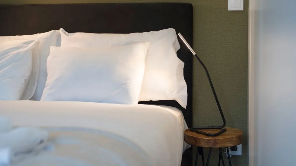 A neatly made bed with white bedding and a dark headboard.