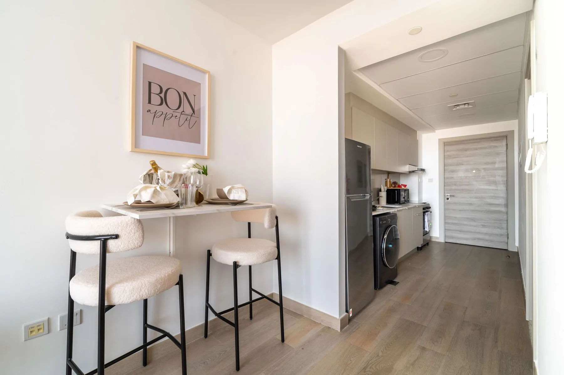 Un luminoso rincón de comedor con una mesa pequeña y asientos junto a una cocina compacta.