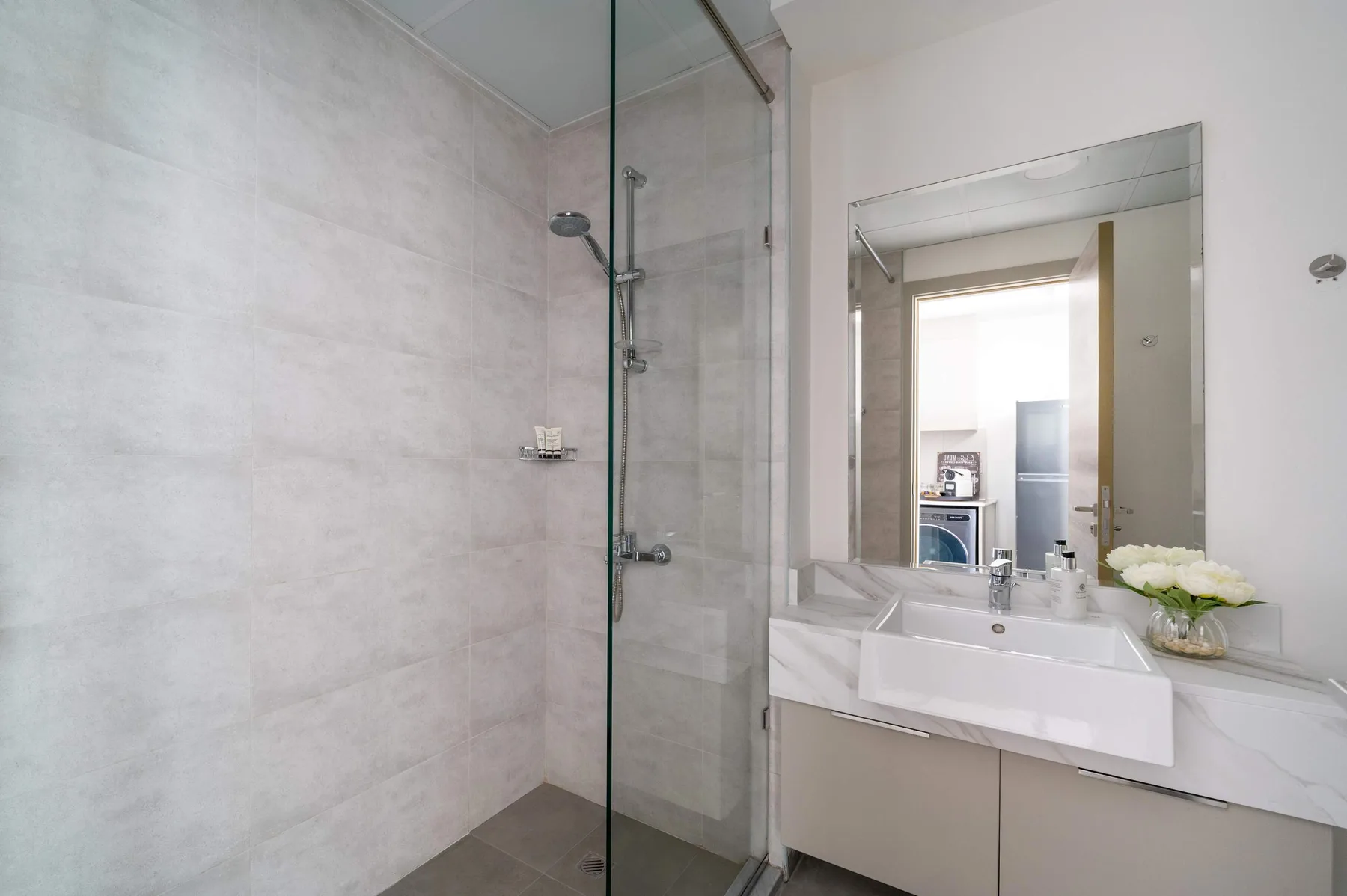 Un baño con ducha de vidrio y un lavabo bajo un espejo grande.