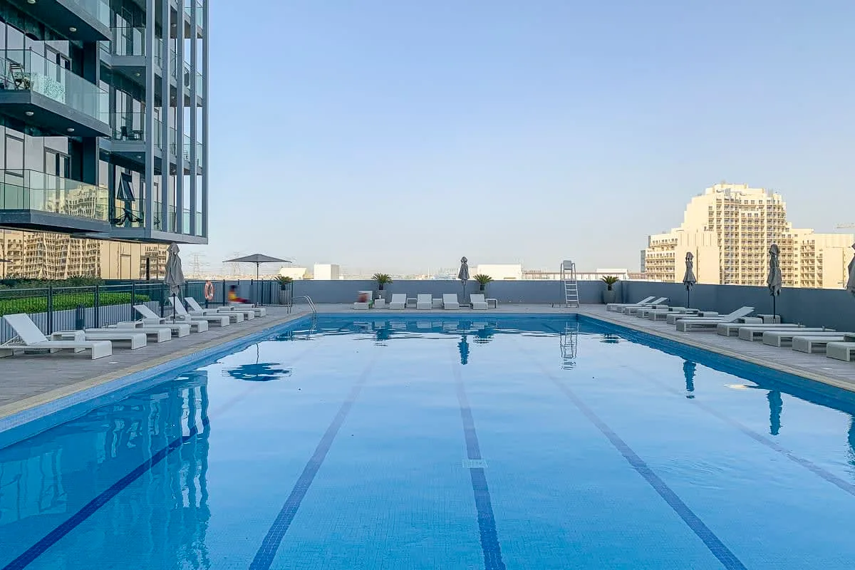 Una piscina en la azotea con asientos y edificios de la ciudad alrededor.