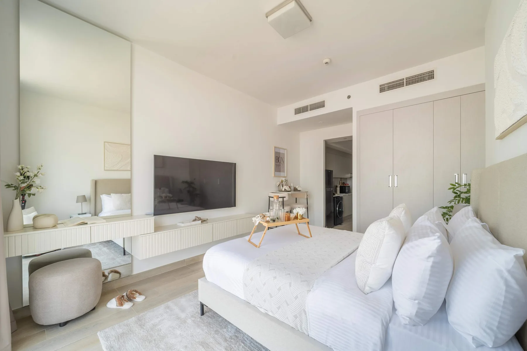 Un dormitorio luminoso con una cama grande, un televisor y armarios empotrados.