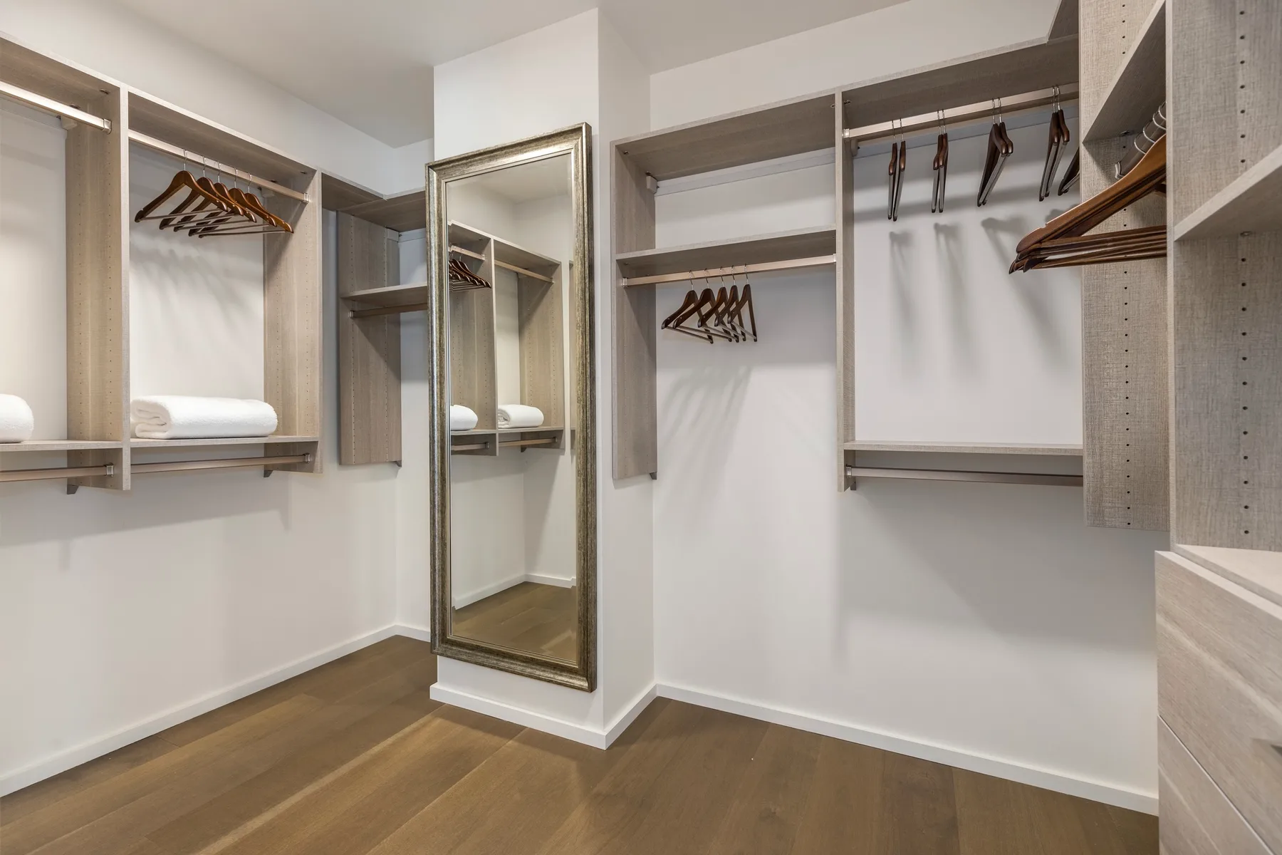 A walk-in closet with open shelving, hanging rails, and a full-length mirror.