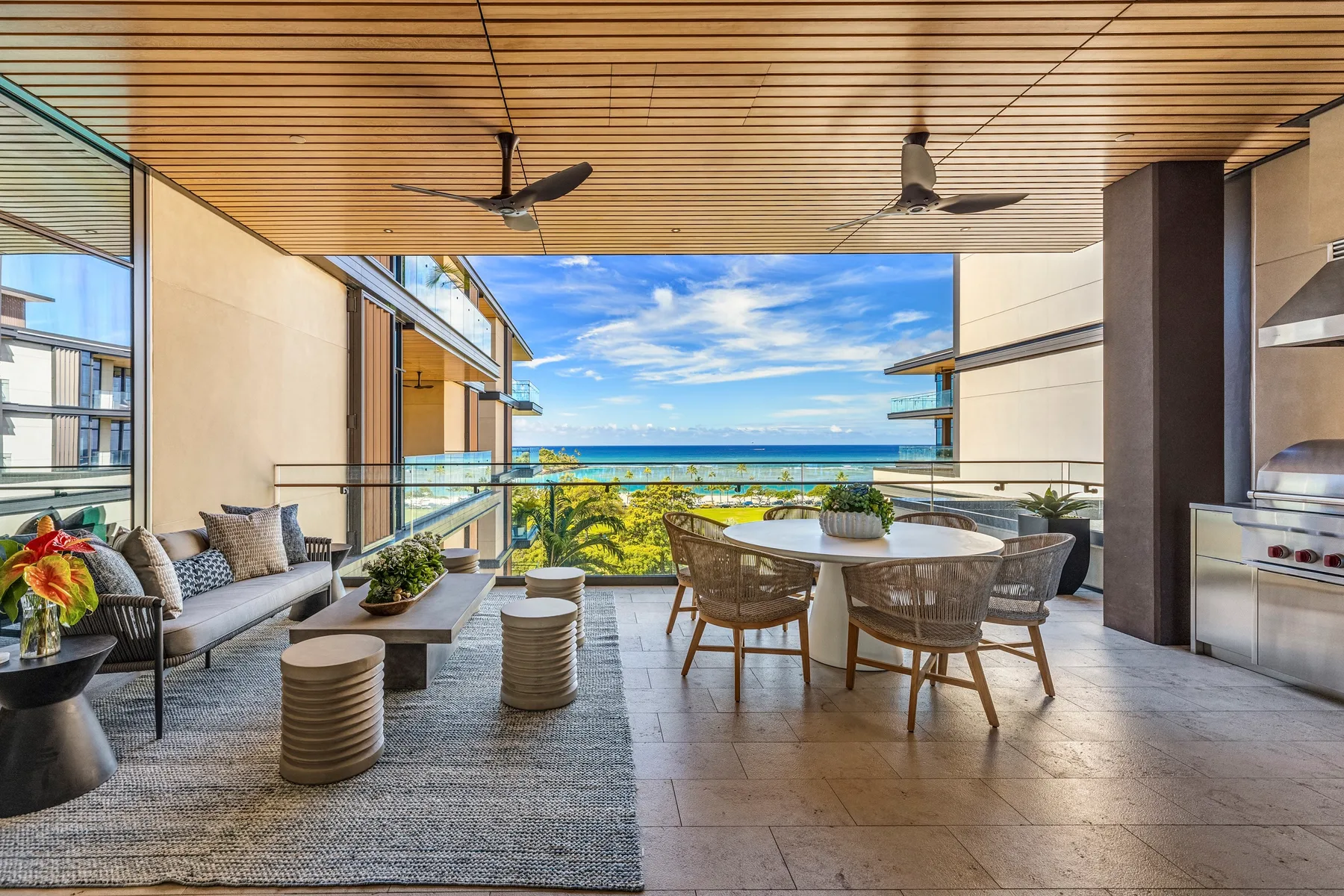 An open-air dining and lounge area overlooks the sea, with a table and seating.