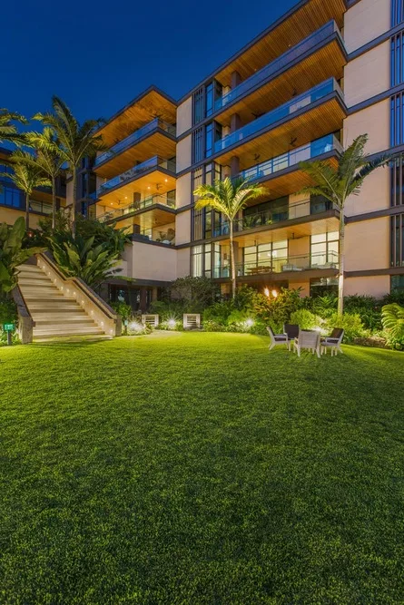 A landscaped lawn with outdoor seating in front of a modern multi-story building.