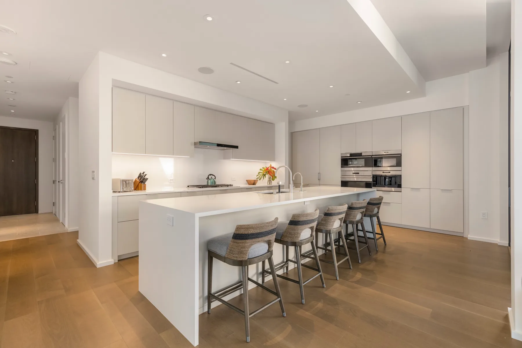 A bright modern kitchen with white cabinetry, a large island, and bar seating.
