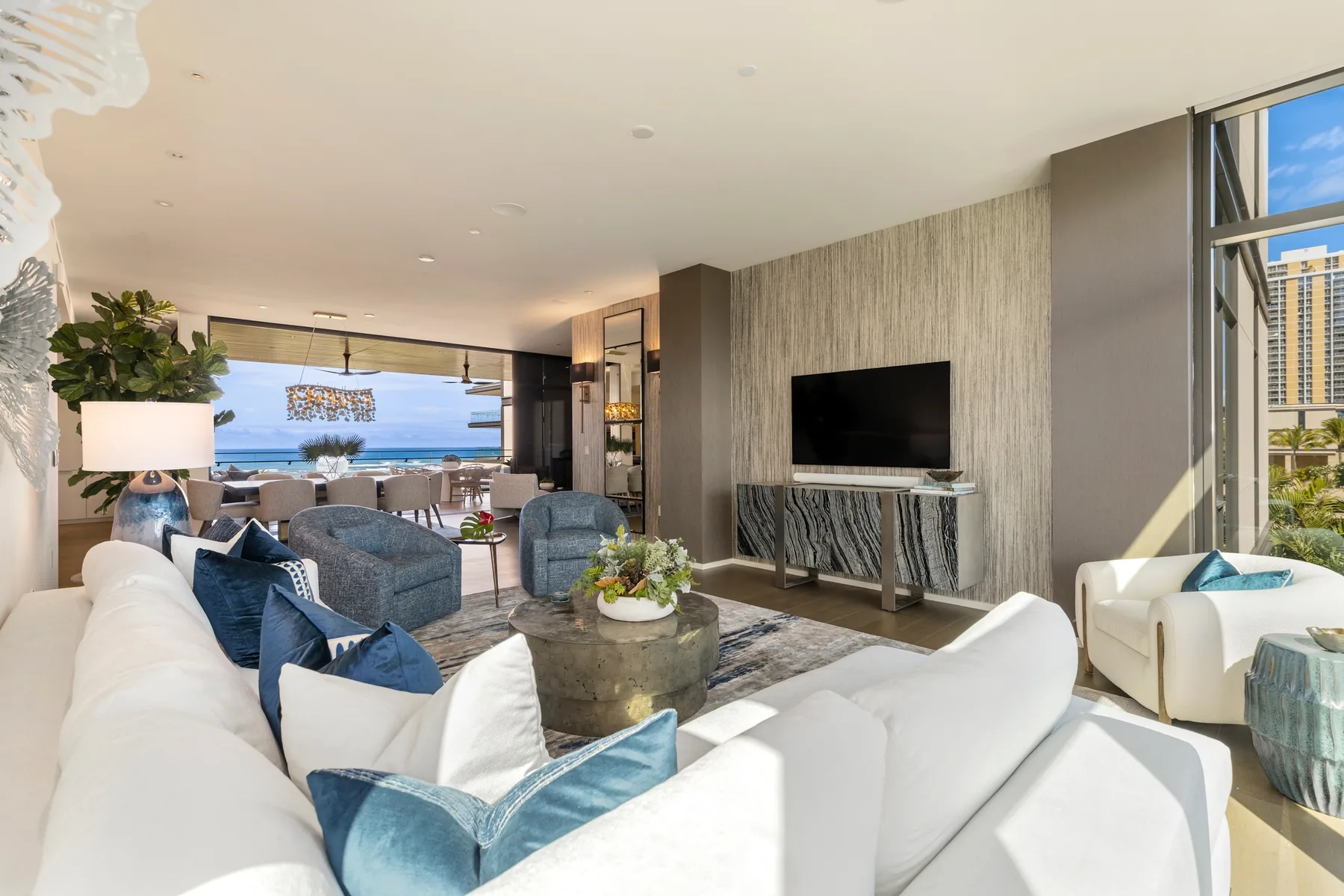 A bright living room with seating around a coffee table and a television.