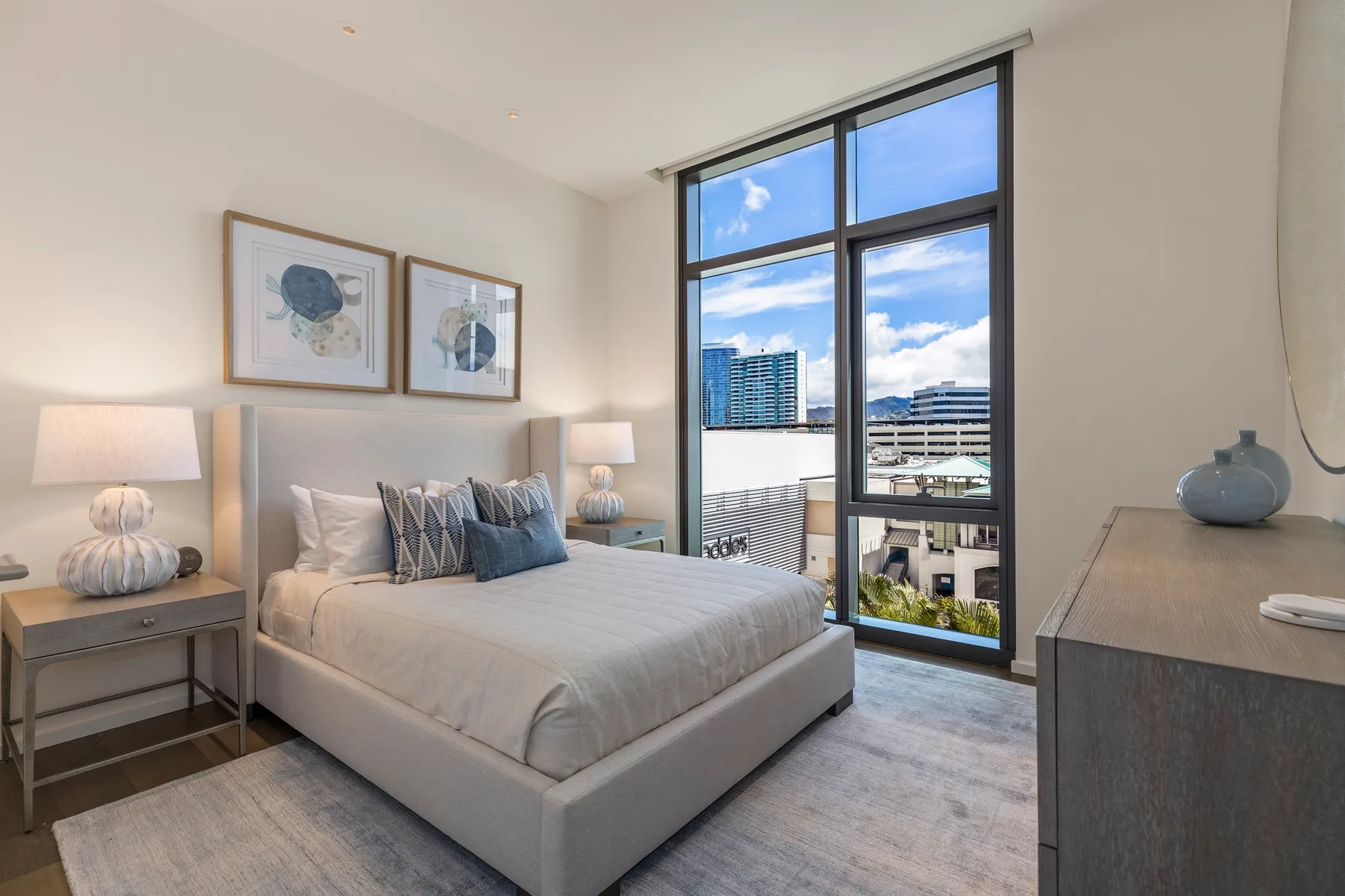 A bright bedroom with a neatly made bed beside a large window.