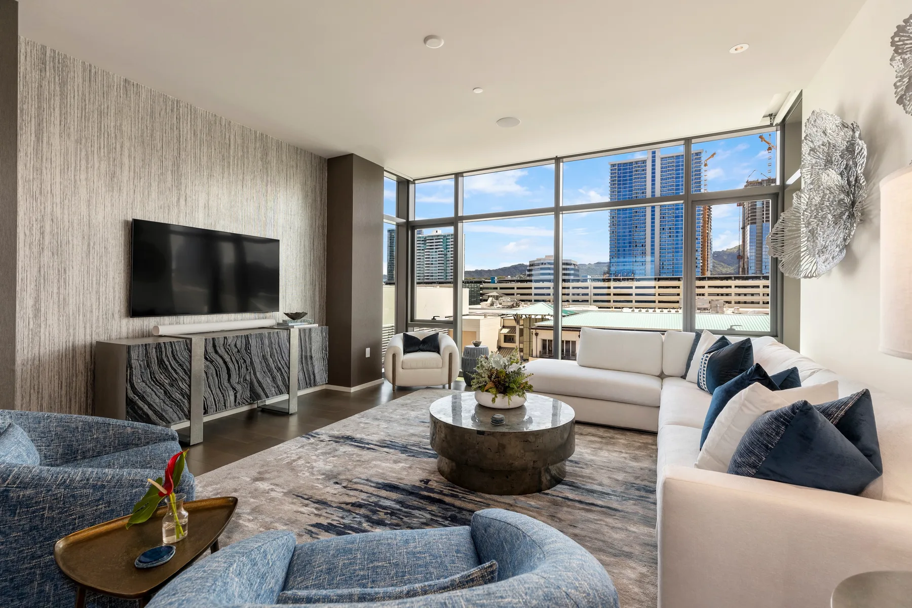 A bright living room with large windows and seating around a coffee table.