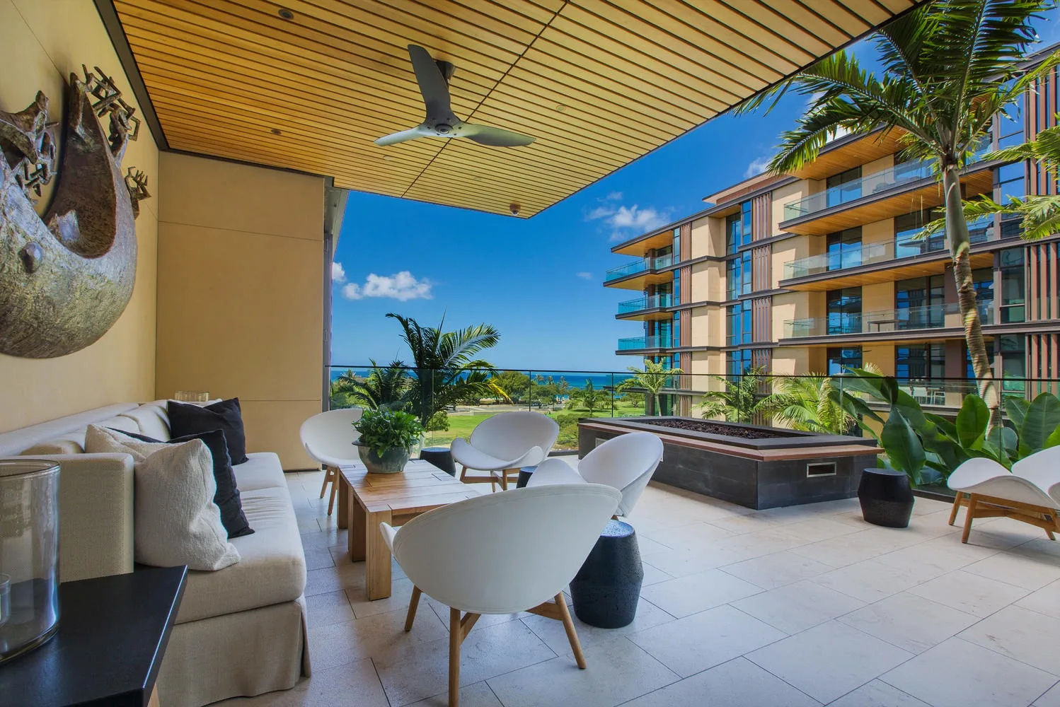A furnished outdoor terrace overlooks the ocean, with seating and a wooden dining table.