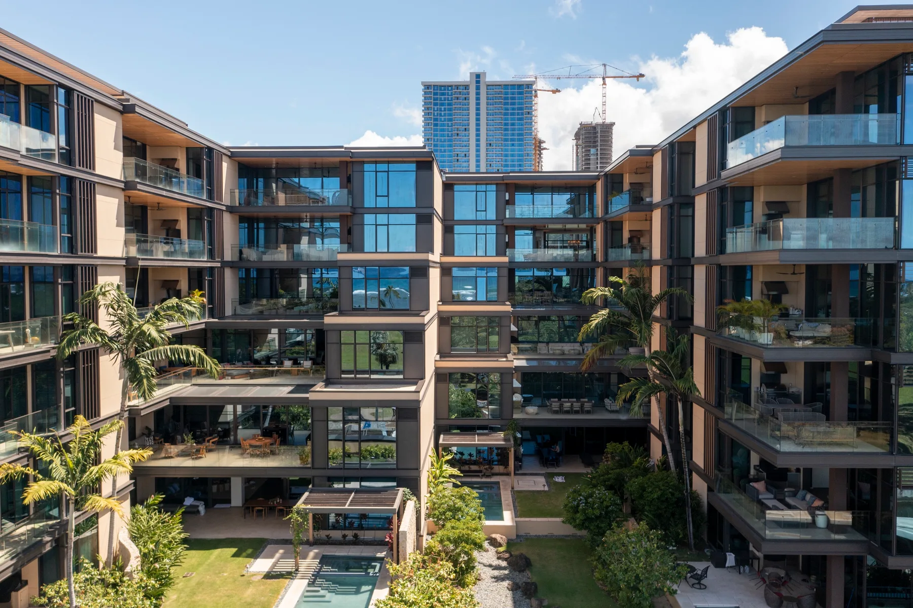 A modern apartment complex surrounds a landscaped courtyard with a small pool.