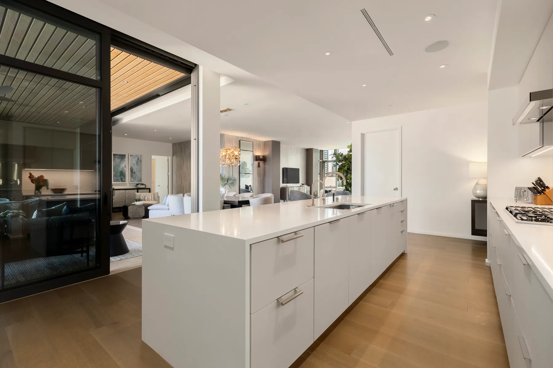 A bright modern kitchen with a large island and an adjoining living area.