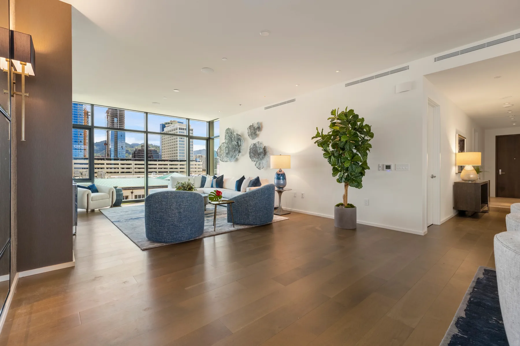A bright living room with seating beside large windows overlooking the city.