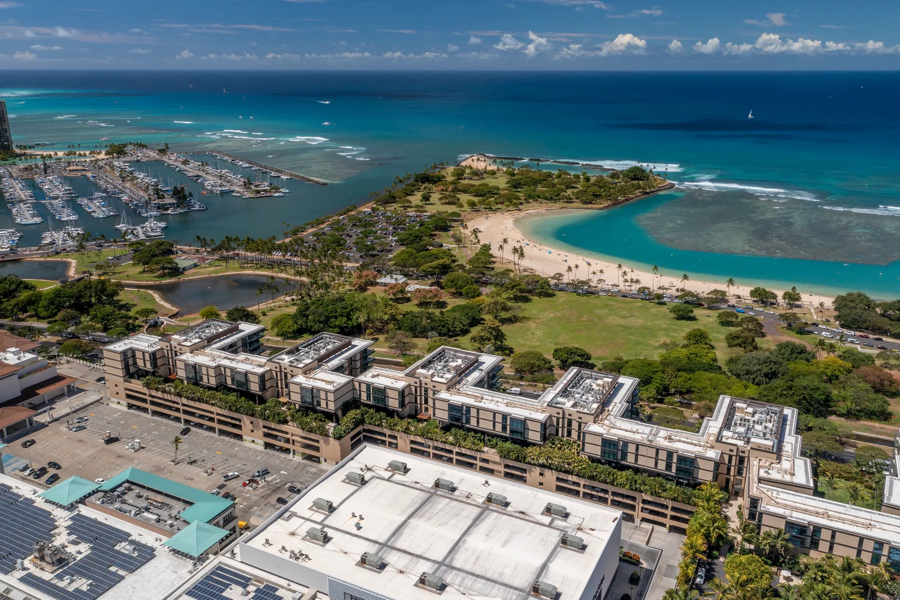 Aerial view of a coastal neighborhood beside a curved beach and turquoise bay.
