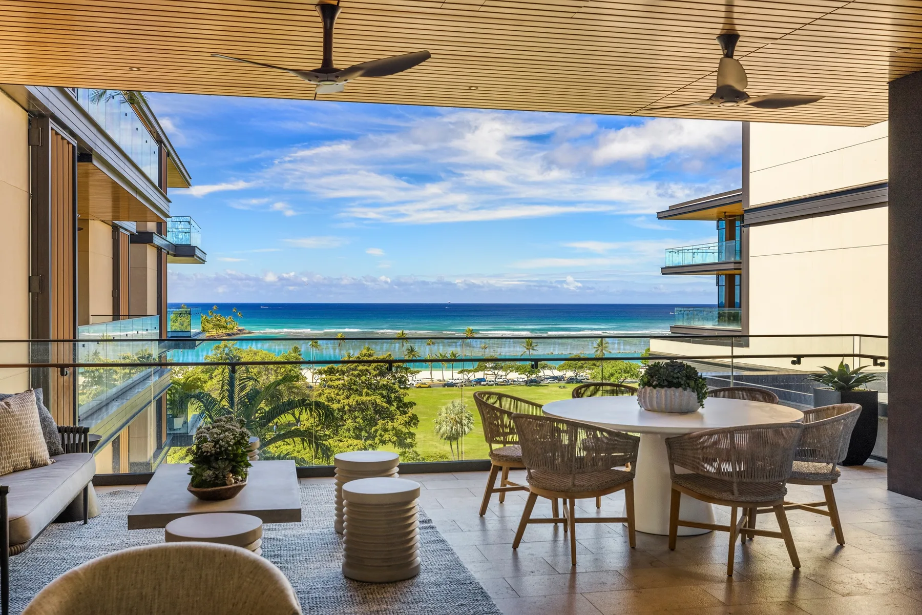 A balcony dining area overlooks the ocean, with outdoor seating and plants.