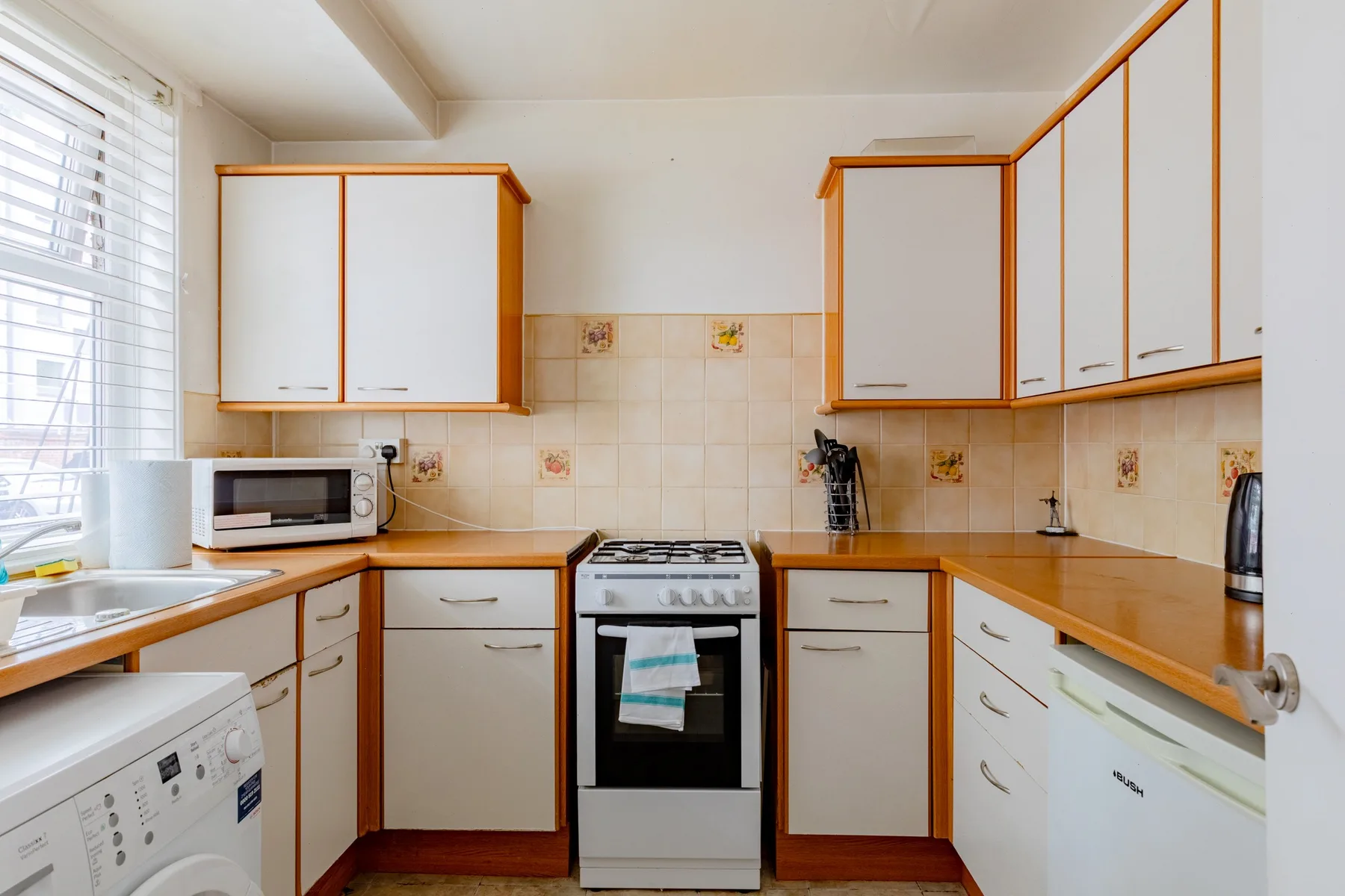 A bright kitchen with white cabinets, wooden countertops, and a stove.