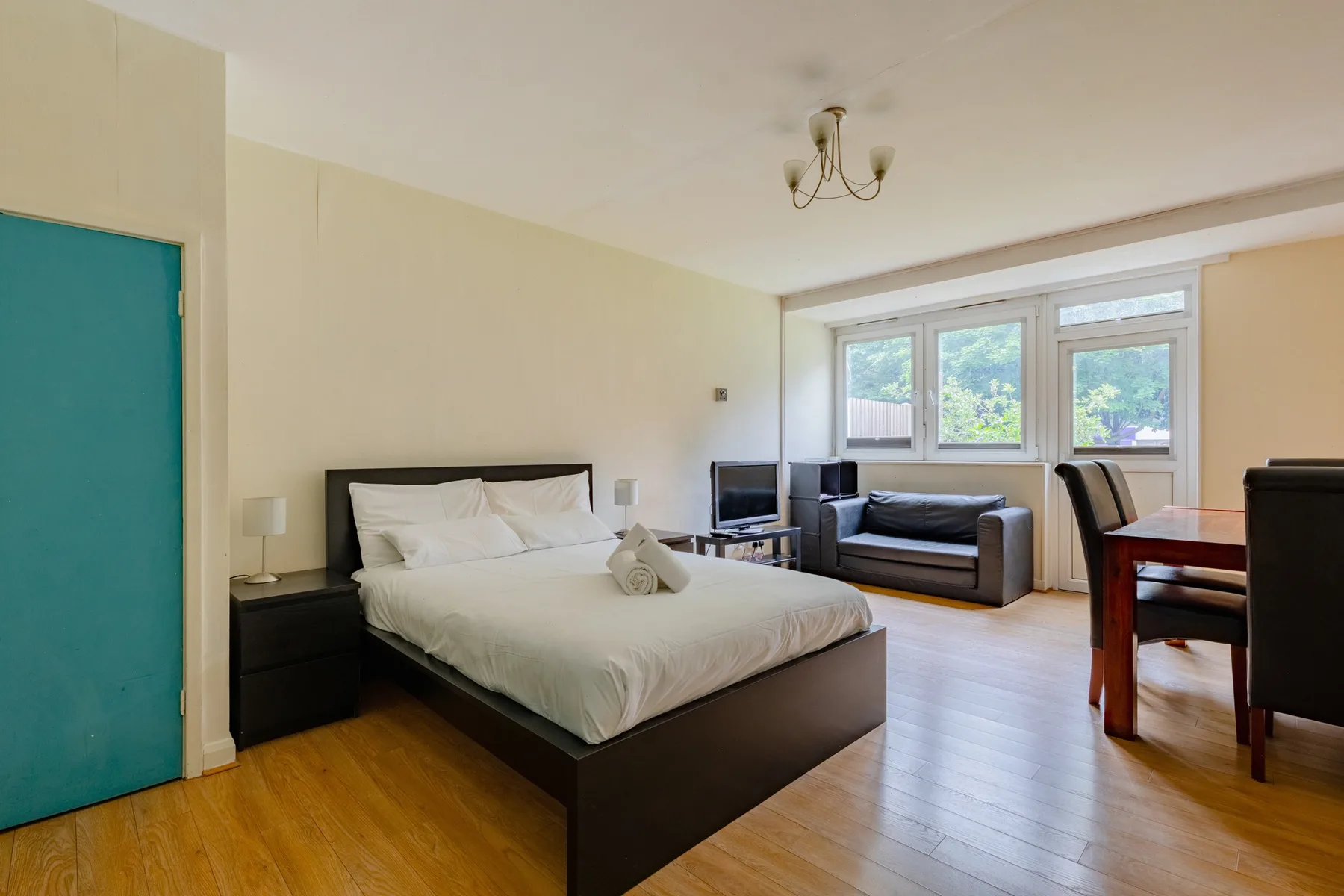A bedroom with a large bed, a seating area, and windows.