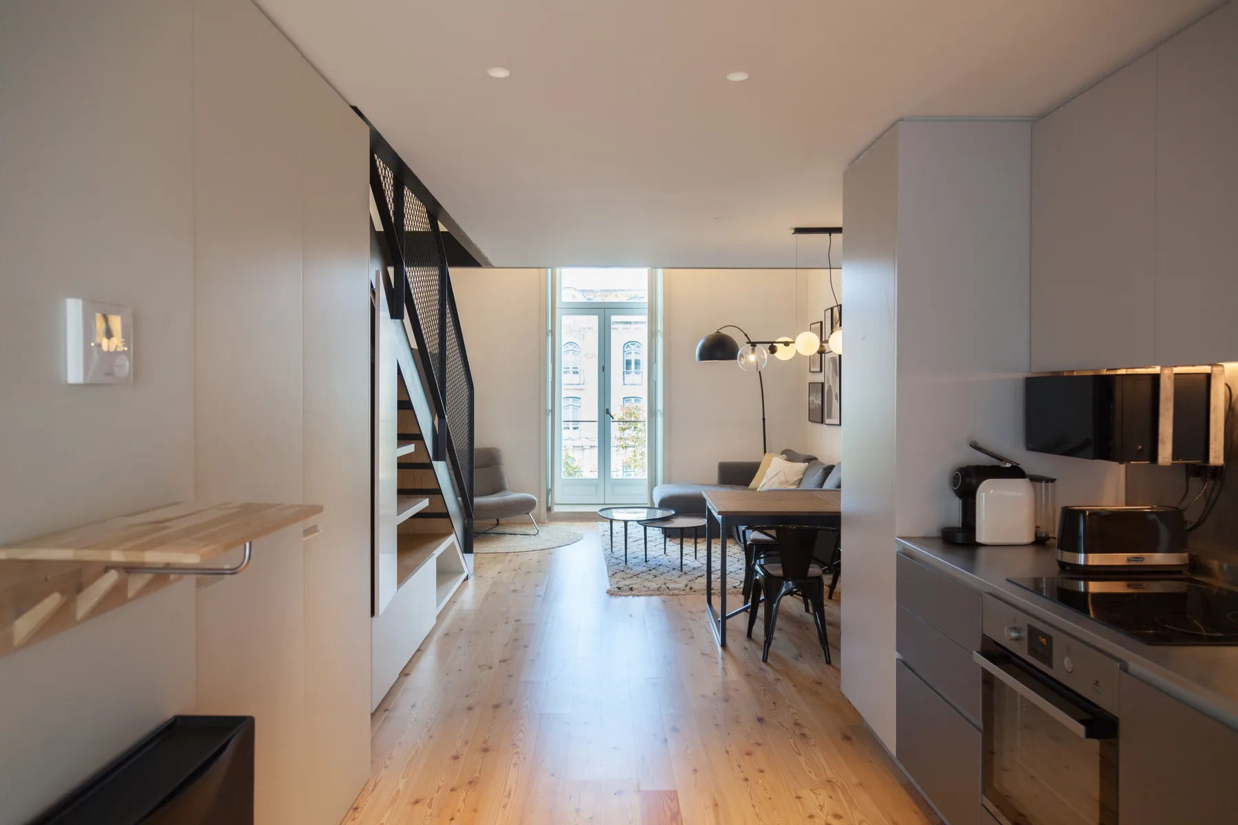 Interior de apartamento moderno con cocina, comedor y asientos junto a ventanales.