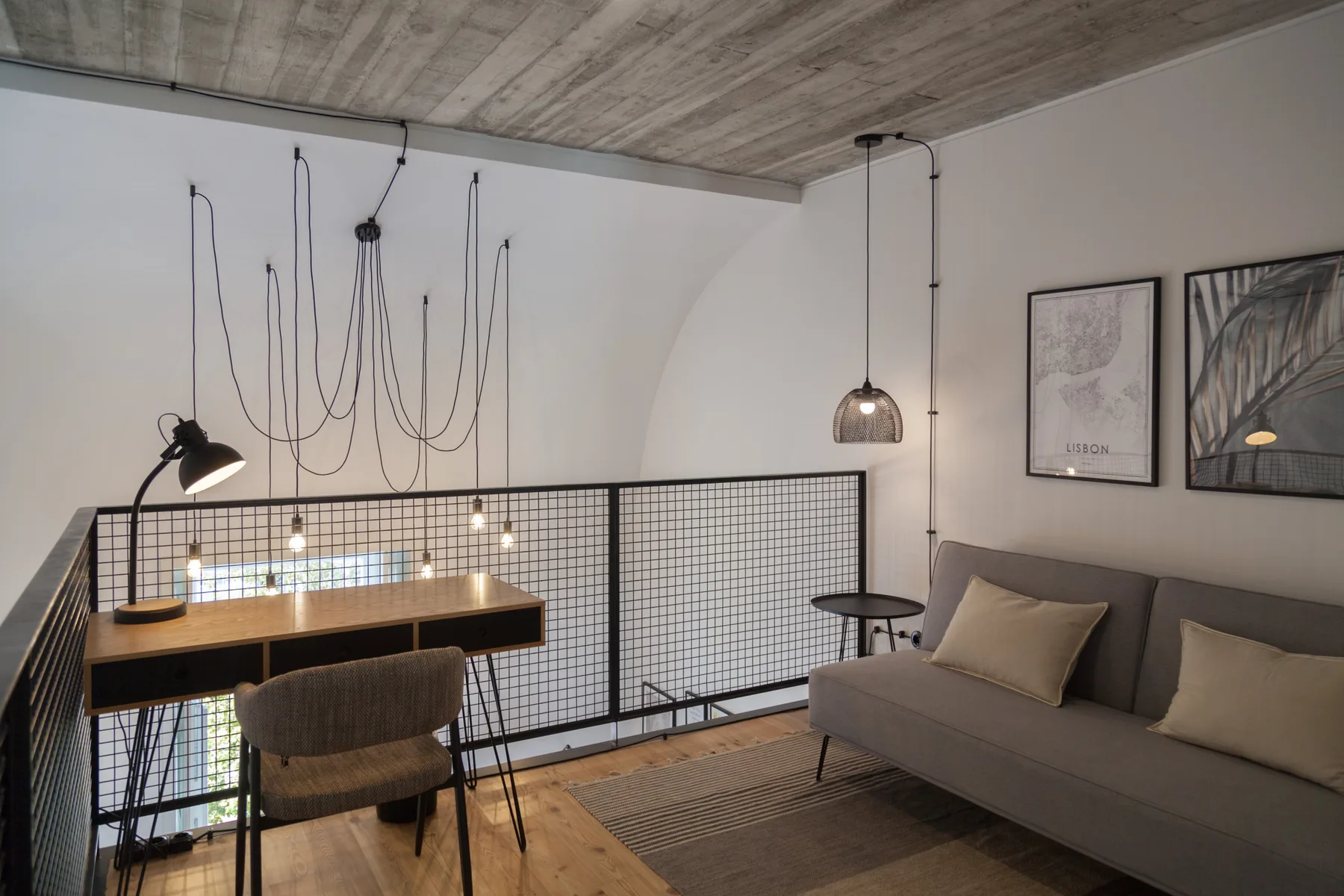 Una sala de estar moderna con sofá, mesa y lámparas colgantes.