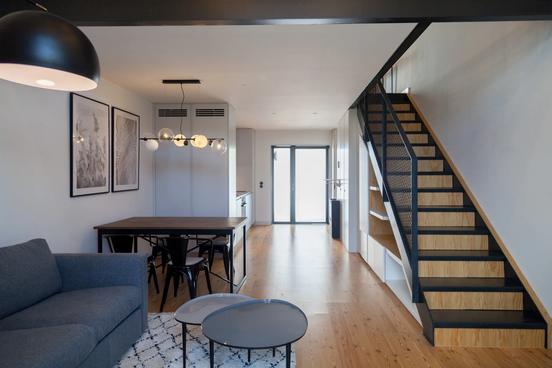Una luminosa sala-comedor diáfana tiene asientos, una mesa y una escalera.