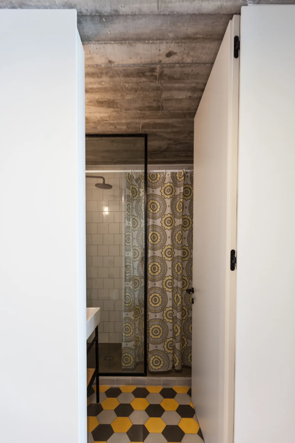 Un baño con una cortina de ducha estampada y suelo de baldosas.