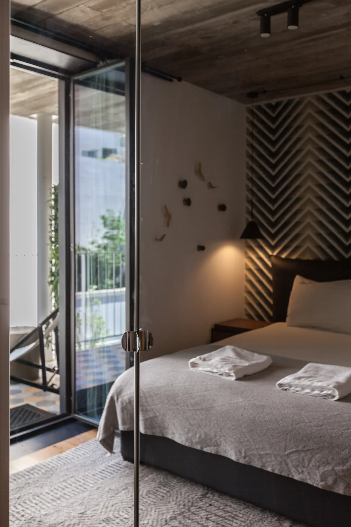 Un dormitorio con una cama junto a puertas de vidrio que dan a un balcón.