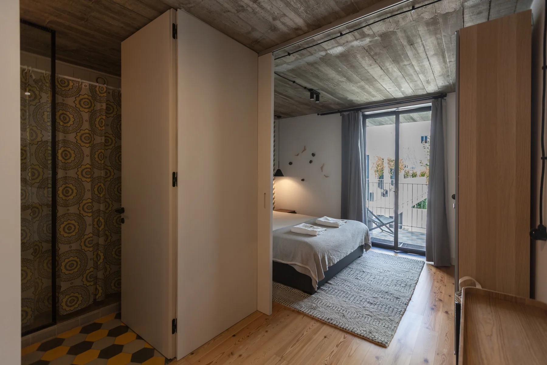 Un dormitorio con una cama junto a puertas correderas de cristal que dan a un balcón.