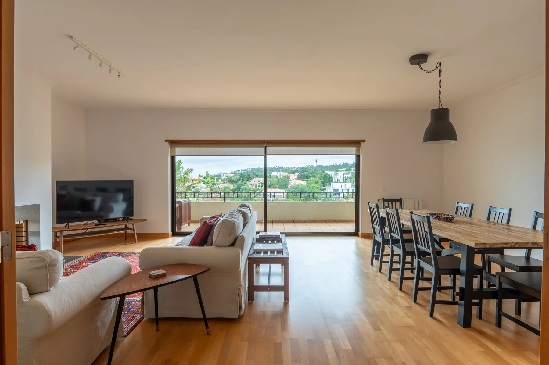 A living and dining room opens onto a balcony through wide glass doors.