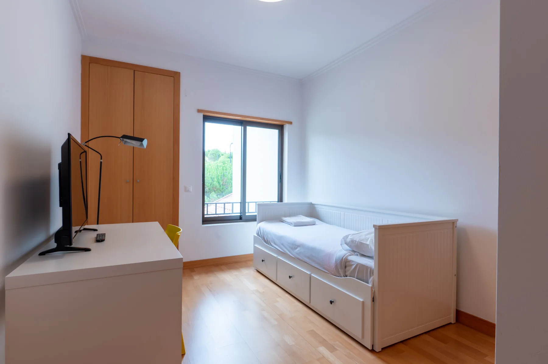 A bedroom with a single bed, desk, and window.