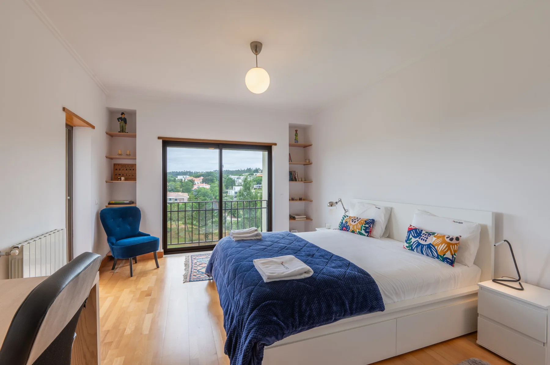 A bedroom with a large bed and a sliding glass door opening onto a balcony.