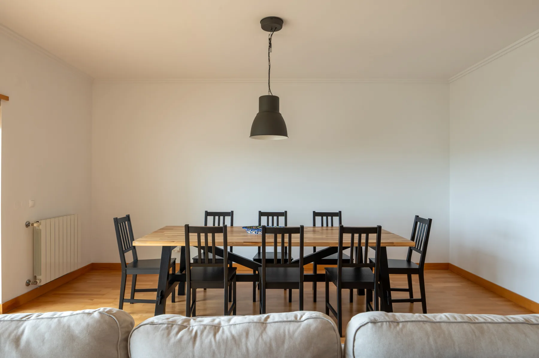 A dining area with a long table and chairs in a bright room.